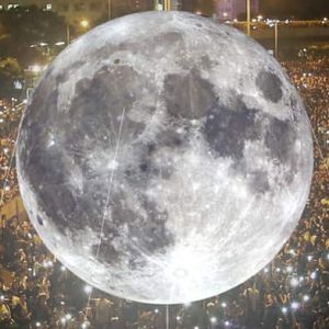Picture: Giant moon balloon being lifted up by a crowd.