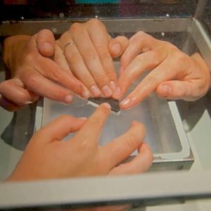 Picture of hands touching a moon rock at a NASA center.