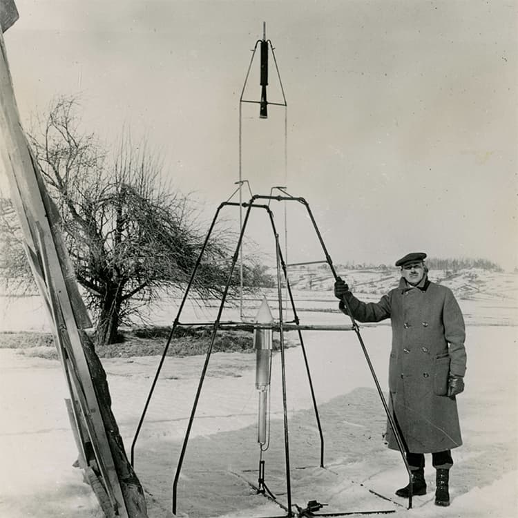 Picture of Dr. Robert Goddard standing next to his first rocket.