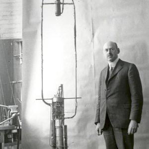 Picture of Robert Goddard posing next to his rocket.